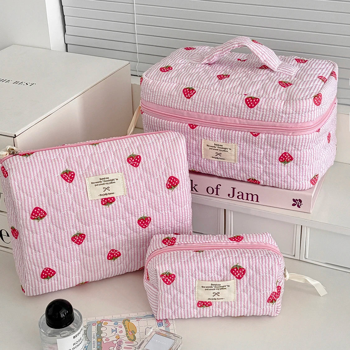 1PC Pink Strawberry Women Cosmetic Quilted Bag set displayed on a countertop with beauty products.